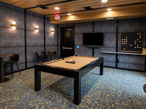 Resident game room with pool table, television and café seating at Argento on the Broad apartments in Arden, NC