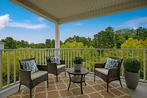 A patio with a table and chairs with a view of trees.