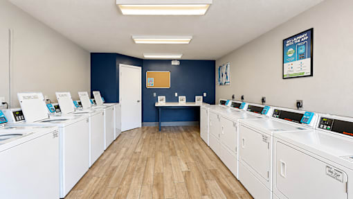 Community laundry room with rows of washers and dryers and a folding counter at Canterbury Apartments in Myrtle Beach, SC.