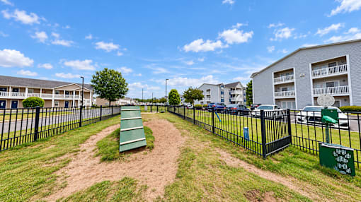 Fenced dog park with an agility ramp and pet waste station at Canterbury Apartments in Myrtle Beach, SC.
