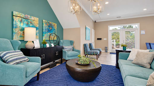 Leasing office lounge with upholstered seating, a round coffee table and coastal artwork at Canterbury Apartments in Myrtle Beach, SC.