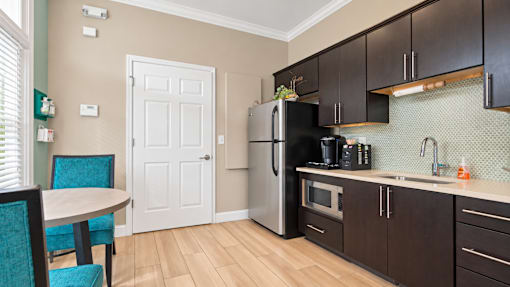 Office kitchenette with dark cabinets, a refrigerator, microwave and coffee station at Canterbury Apartments in Myrtle Beach, SC.