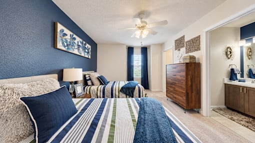 Furnished bedroom with two twin beds and a view of the adjoining bathroom at Canterbury Apartments in Myrtle Beach, SC.