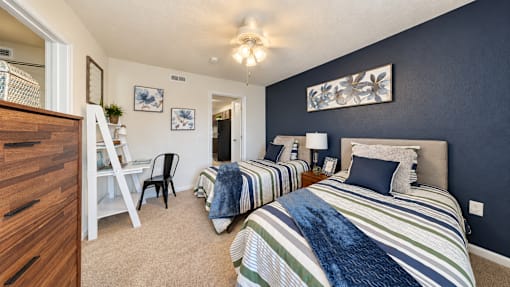 Two twin beds, a compact desk and a dresser in a furnished bedroom at Canterbury Apartments in Myrtle Beach, SC.