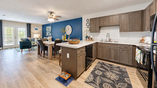 Kitchen with gray cabinets, black appliances and an adjoining furnished living area at Canterbury Apartments in Myrtle Beach, SC.