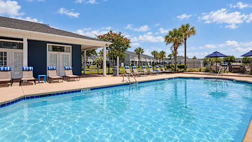 Swimming pool beside the main office, with lounge chairs and palm trees at Canterbury Apartments in Myrtle Beach, SC.