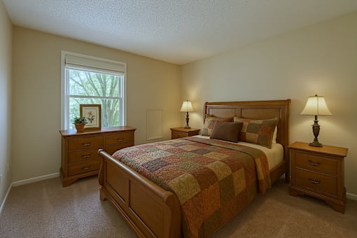 A bedroom with a bed, nightstands, and a window.