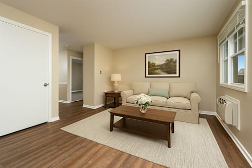 A living room with a couch, coffee table, and a painting on the wall.