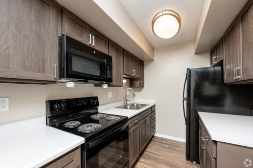 redesigned kitchen with black appliances and white countertops in an apartment