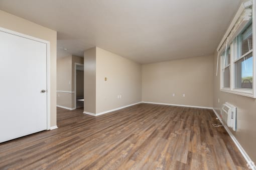 an empty living room with wood flooring and a window