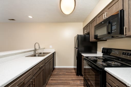 a kitchen with black appliances and white counter tops and wood floors