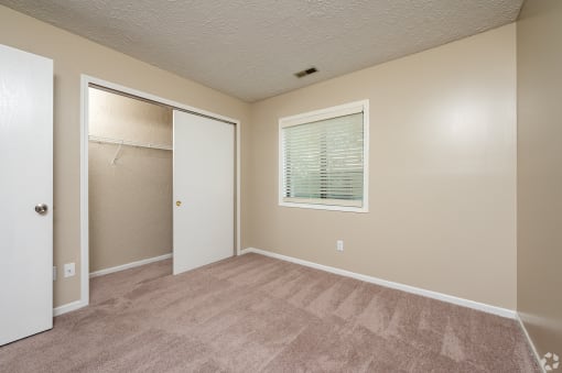 an empty bedroom with a closet and a window