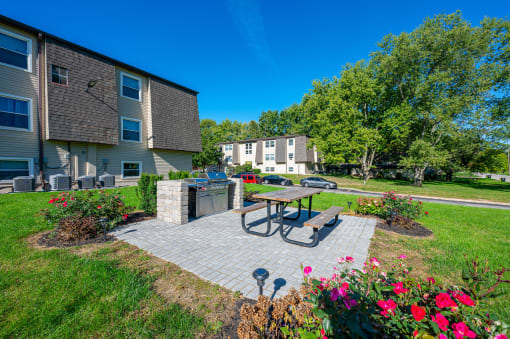 a patio with a picnic table and a grill in front of an apartment building