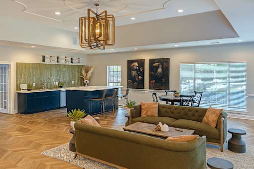 A living room with a green couch and a chandelier.