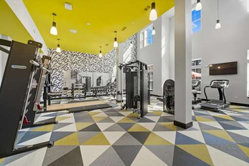 A gym with a variety of equipment and a geometric patterned floor.