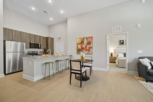 A kitchen with a refrigerator, microwave, and bar stools.