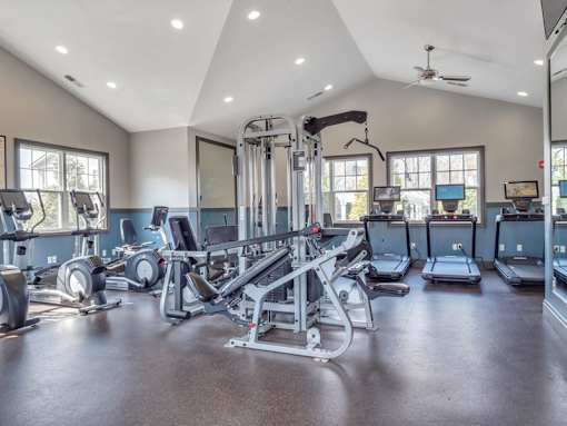 A spacious gym with various exercise equipment and a ceiling fan.