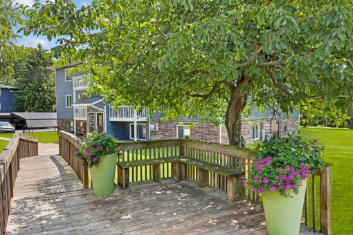 a large wooden deck with a bench and potted plants