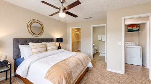 Furnished bedroom with a ceiling fan, walk-in closet opening, and nearby bathroom at Icon Cartersville Apartments.