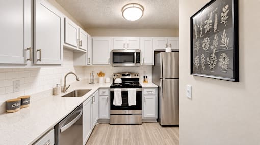 Apartment kitchen with white cabinets, subway tile backsplash, and stainless steel appliances at Icon Cartersville.