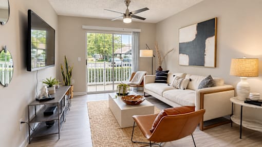 Furnished living room with a sofa, accent chairs, ceiling fan, and sliding door to a balcony at Icon Cartersville Apartments.
