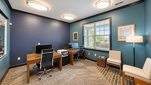 Resident business center with computer workstations, a printer, desks, and seating at Icon Cartersville.