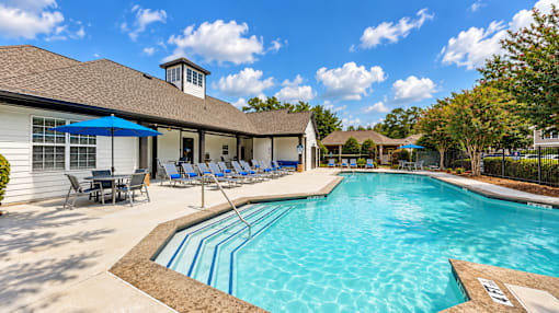 View across the Icon Cartersville swimming pool toward lounge chairs, umbrellas, and the clubhouse.