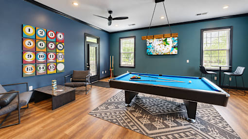 Resident lounge with a blue-felt pool table, seating, television, and numbered wall art at Icon Cartersville.