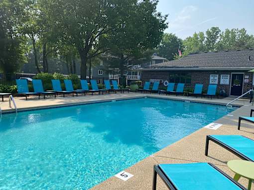 A pool with blue chairs and a building in the background.