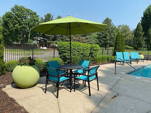 A green umbrella is above a table with chairs around it.