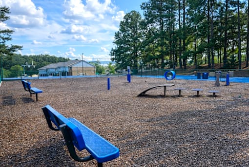 A playground with blue benches and a swing set.