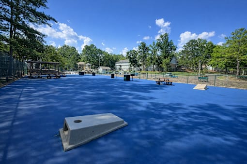 A playground with a blue surface and a slide in the foreground.