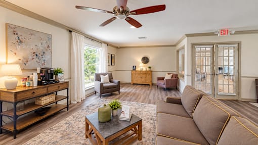 A living room with a brown couch, a coffee table, and a ceiling fan.