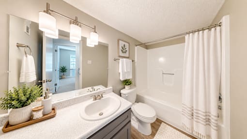 Apartment bathroom with vanity, tub and shower combination, and wood-style flooring at Madison Park Apartments & Townhomes in Birmingham, AL.