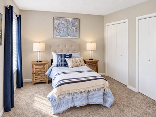 Bedroom with carpet, closet storage, and blue-accented furnishings at Madison Park Apartments & Townhomes in Birmingham, AL.