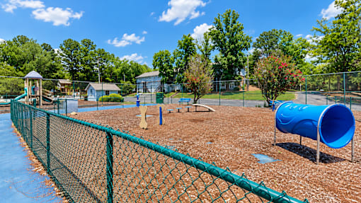 A playground with a blue slide and a green fence.
