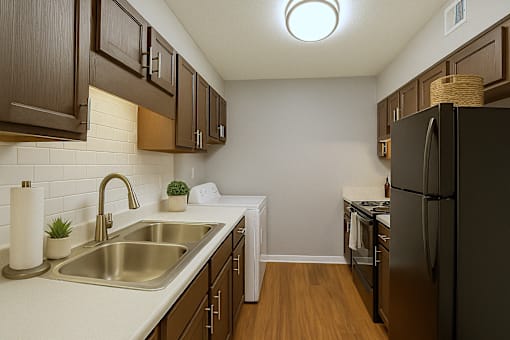 A kitchen with a black refrigerator and brown cabinets.