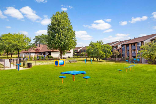 a park with a blue picnic table and benches in front of some apartments