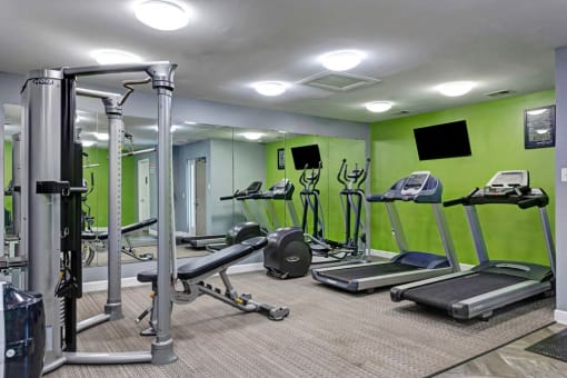 a gym with weights and other equipment and green walls