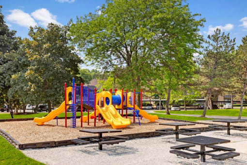 a playground with slides and picnic tables in a park