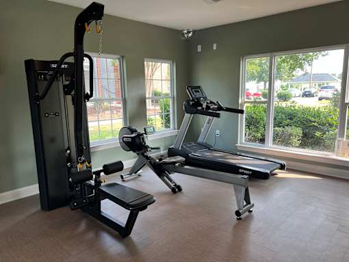 A gym with a treadmill, a stationary bike, and a weight machine.