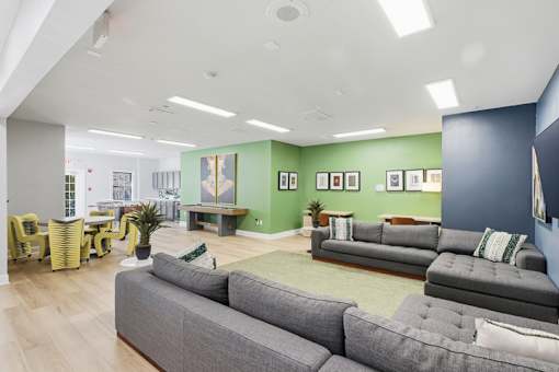 A living room with grey couches and yellow chairs.