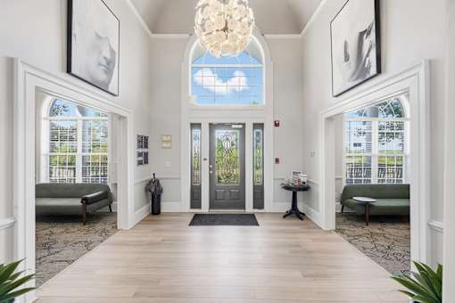 A hallway with a chandelier, two sofas, and pictures on the wall.