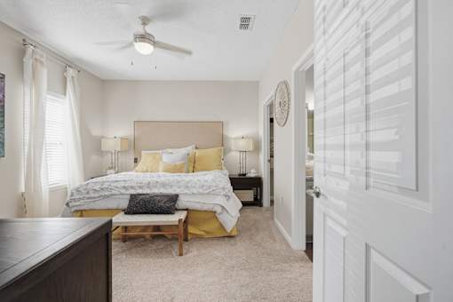 A bedroom with a bed, nightstands, and a ceiling fan.