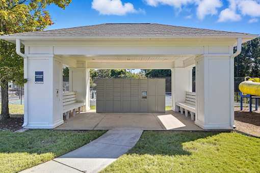 A white pavilion with a brown roof and a yellow object in the background.