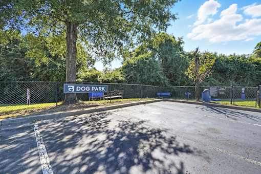 A sign for Dog Park is seen in front of a fence.
