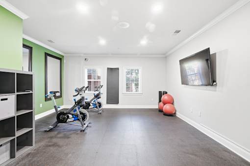 A room with a green wall and a grey floor with a TV on the wall.