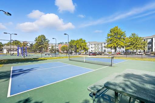 A tennis court with a green bench in the foreground.