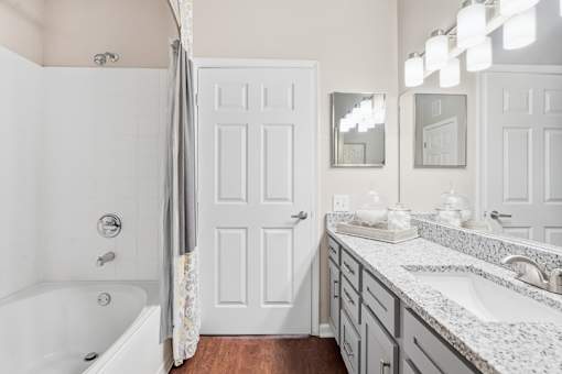 A white bathroom with a tub, sink, and mirror.