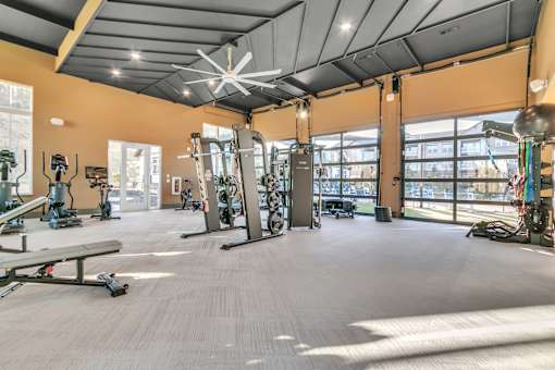 A gym with a variety of exercise equipment and a large mirror on the wall.